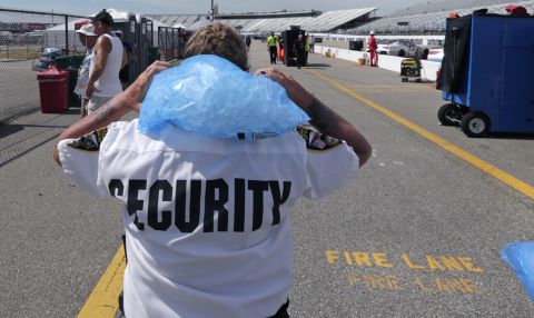Track security officer Patty Patterson carries a bag of ice on her shoulders as she walks back to her post during a NASCAR Cup Series auto race practice at New Hampshire Motor Speedway in Loudon, New Hampshire, on July 20.