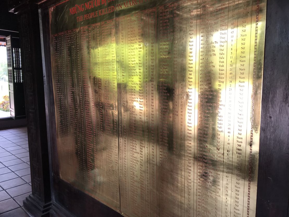 The reflections of visitors look ghostlike from a golden wall containing names of the victims of the My Lai massacre in central Vietnam.