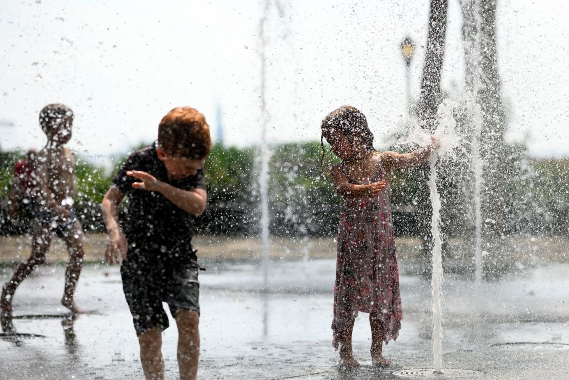 Children cool down by playing in a public fountain during the summer heat on July 19 in New York.