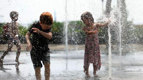 Children cool down as they play in a public fountain during summer heat in New York City. 