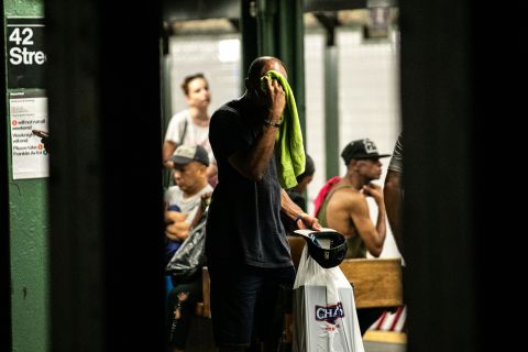A man wipes his face with a towel while standing on subway platform in New York on July 20.