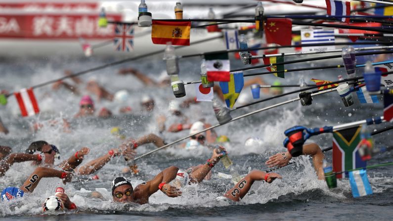 Swimmers reach for water bottles while competing in the men's 10km open water swim at the World Swimming Championships in Yeosu, South Korea, on Tuesday, July 16.