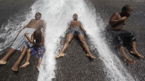 Kids play in an open fire hydrant during the heat wave in Detroit.