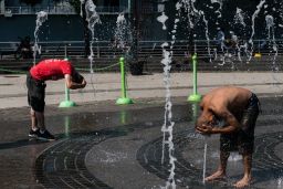 People cool off in a splash pad at a park in New York.