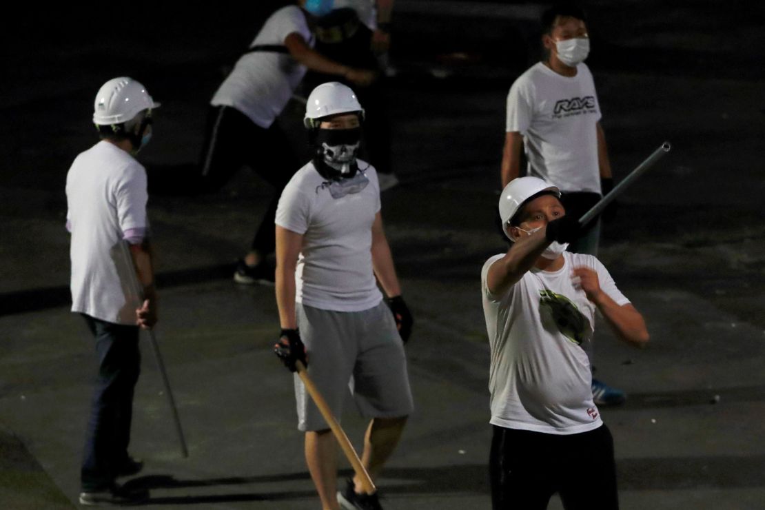Men in white T-shirts with poles are seen in Yuen Long after attacking anti-extradition bill demonstrators at a train station, in Hong Kong.