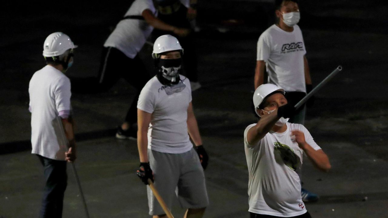 Men in white T-shirts with poles are seen in Yuen Long after attacking anti-extradition bill demonstrators at a train station, in Hong Kong.