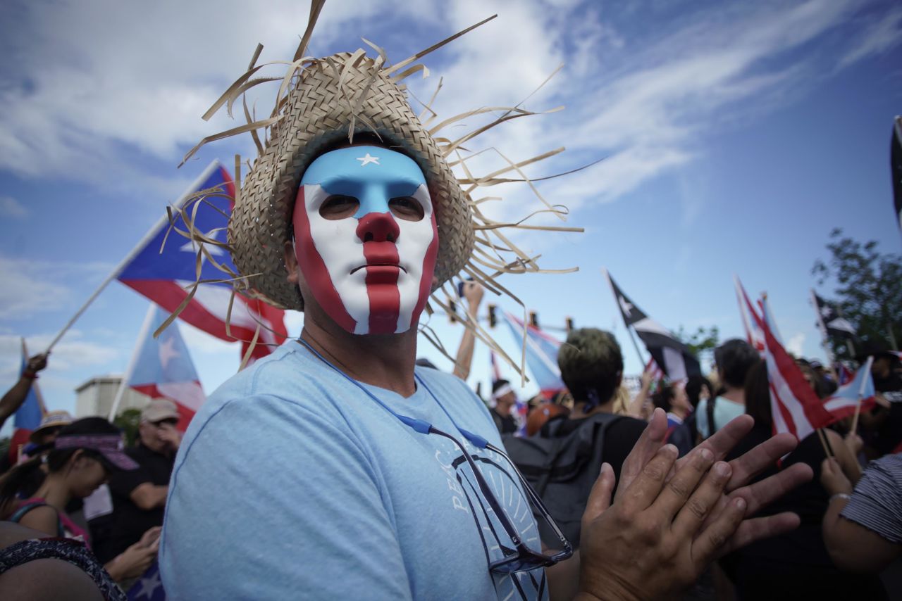 A masked man protests in San Juan.