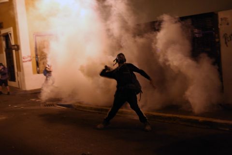 A protester throws a tear gas canister toward police in San Juan.