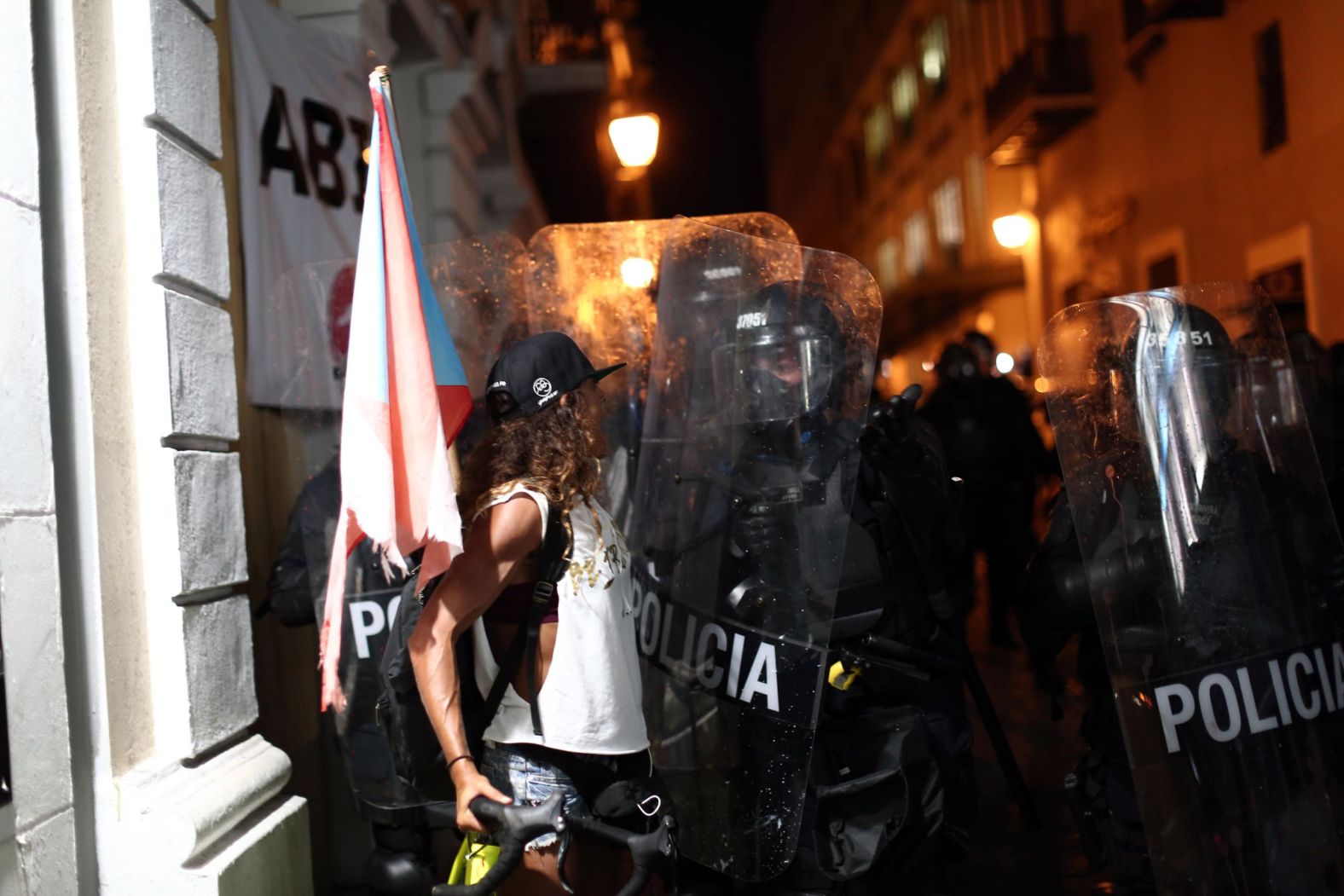 A woman confronts police in riot gear.