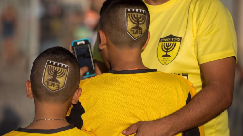 Supporters of Israeli football club Beitar Jerusalem enter the stadium bearing the club's shield on their heads prior to their return match against Belgium team Charleroi on July 23, 2015 at Teddy Stadium in Jerusalem. Beitar Jerusalem owner Eli Tabib announced after the first leg of Europa League match between Charleroi and Beitar was halted in Belgium that he was "ashamed" by the conduct of an "extremist group of fans" and intended to sell the team. AFP PHOTO / MENAHEM KAHANA        (Photo credit should read MENAHEM KAHANA/AFP/Getty Images)