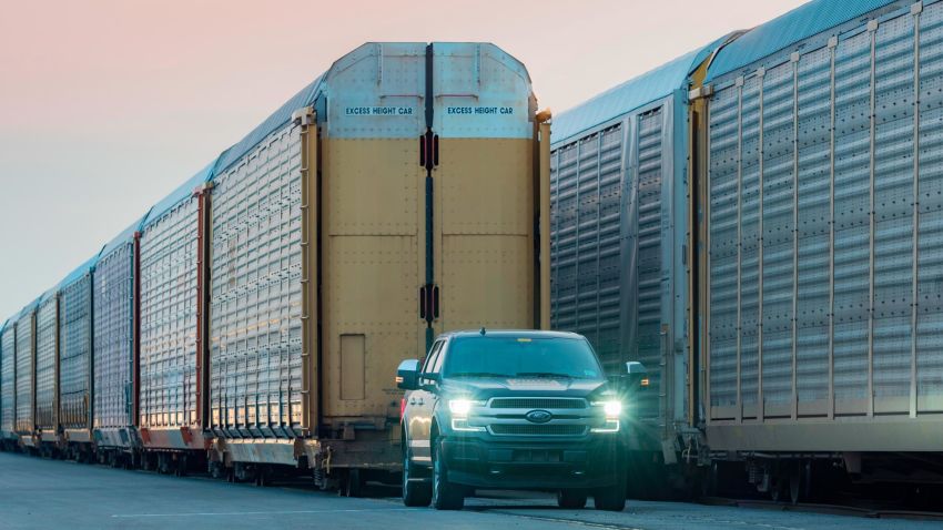 An electric Ford F-150 tows train cars.