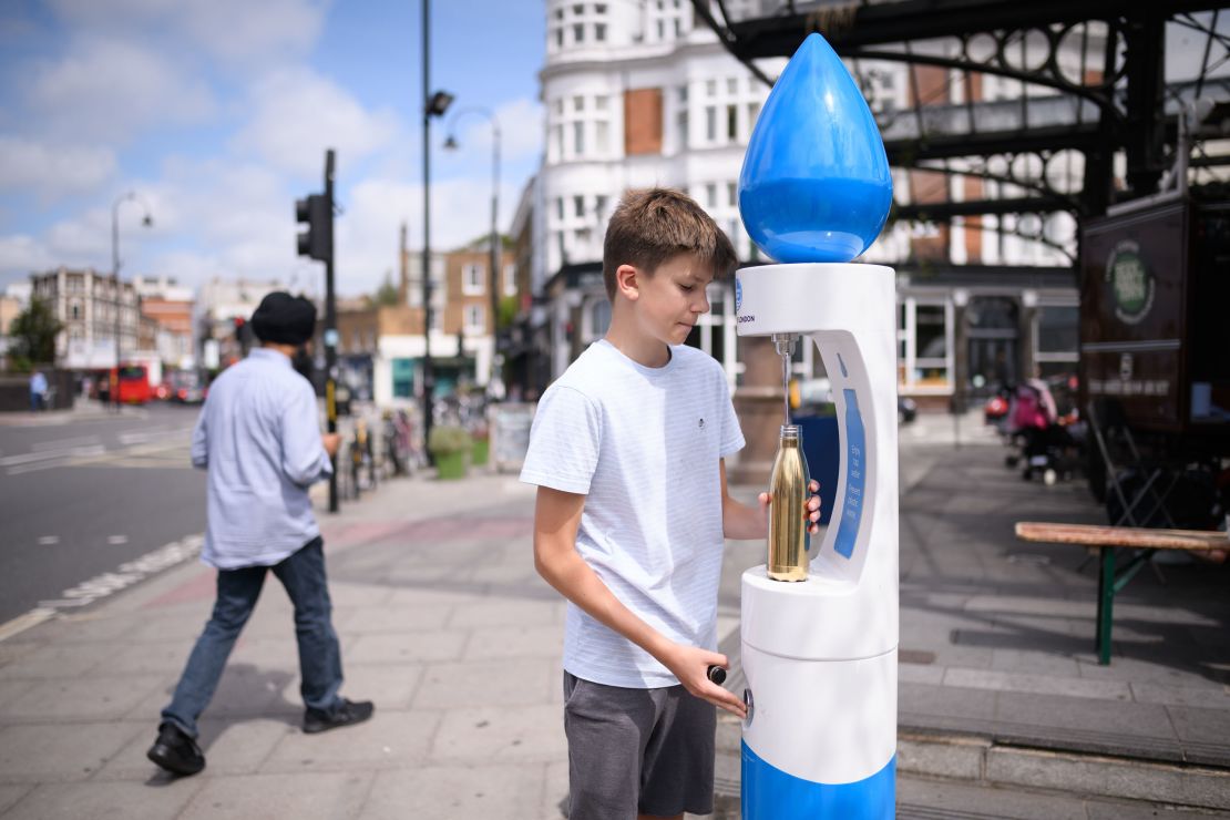 A boy fills a water bottle as temperatures rise in London on Monday.
