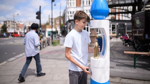 A boy fills a water bottle as the temperature rises in London on Monday. 