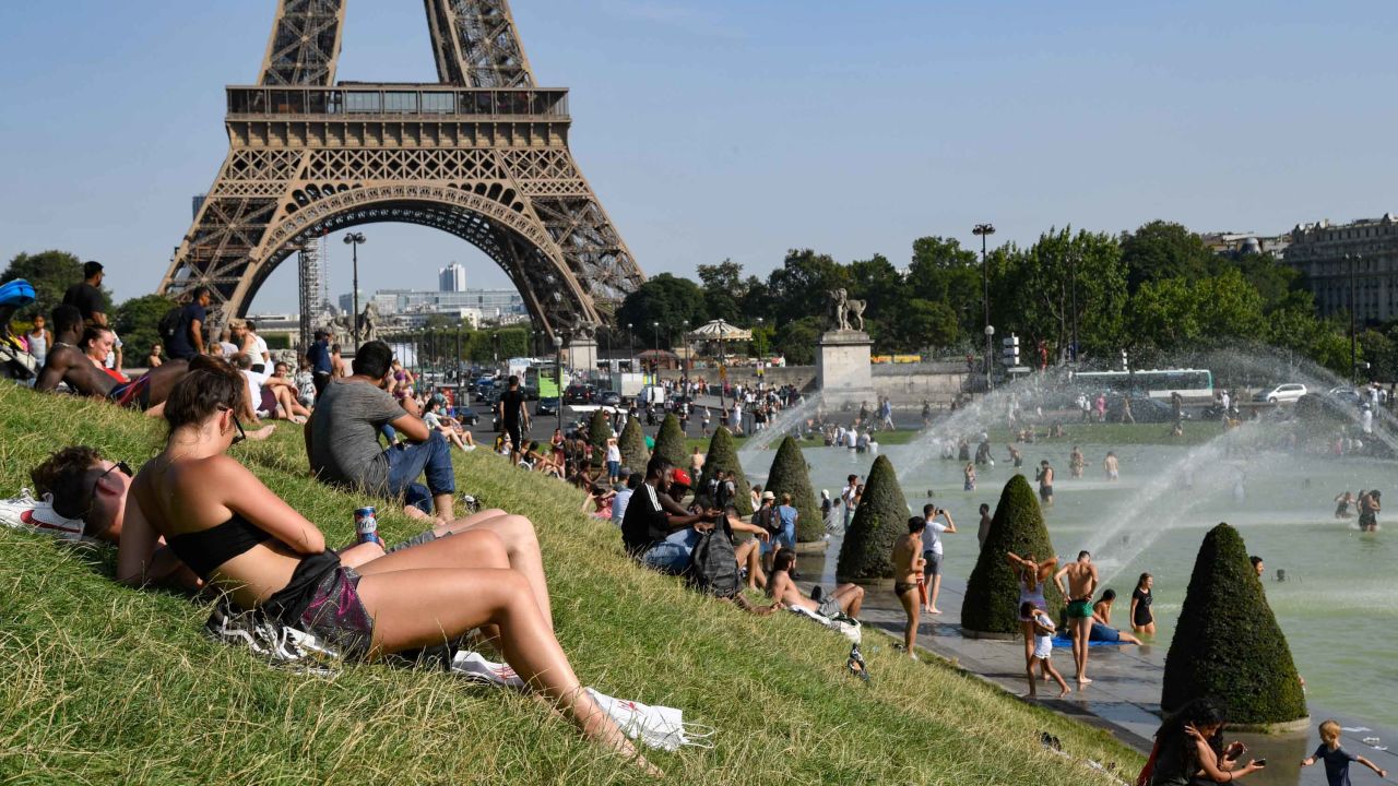 People sunbathe and cool off at the Trocadero Fountains next to the Eiffel Tower in Paris.