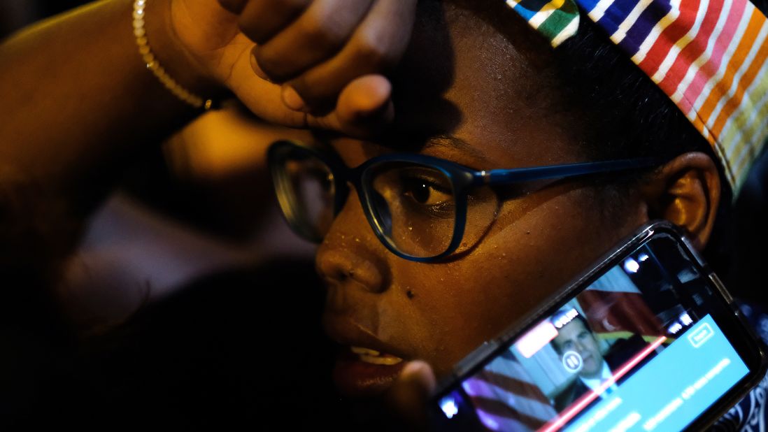 A demonstrator listens to Rosselló's resignation message on a cell phone.