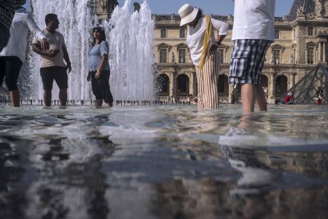 People cool off next to the fountains at the Louvre Museum in Paris on Wednesday, July 24.