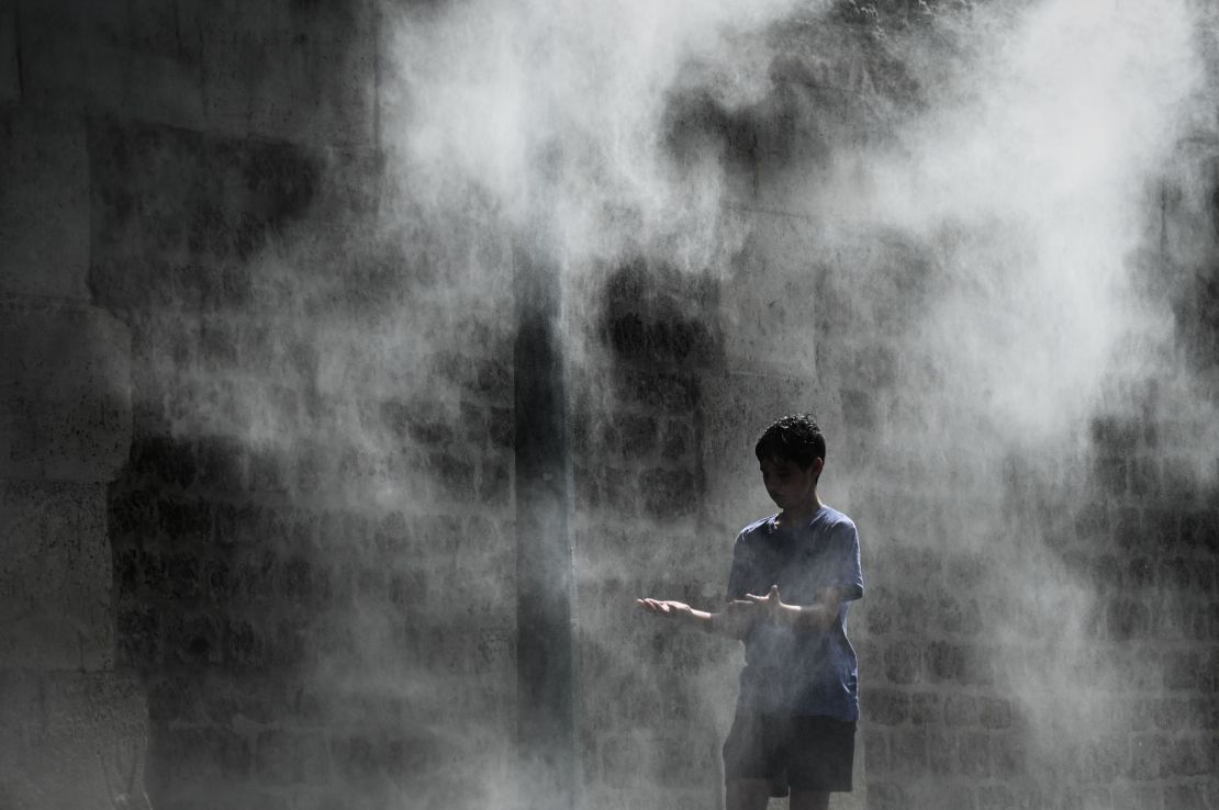 A boy cools off under a public water spray on the bank of the Seine river in Paris.