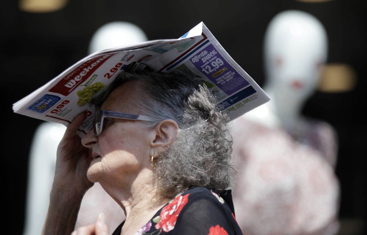 A woman shields herself with a newspaper in Milan, Italy, on Thursday, July 25.