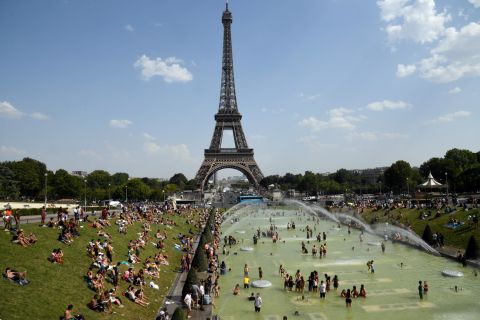 People cool off and sunbathe next to the Eiffel Tower in Paris on Thursday, July 25.