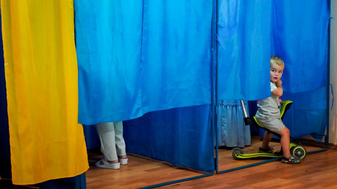 A boy looks out from a voting booth at a polling station in Kiev, Ukraine, on Sunday, July 21.