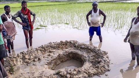 Villagers and farmers pose around the crater of a suspected meteorite that crashed in a field at Mahadeva village in the Indian eastern state of Bihar.