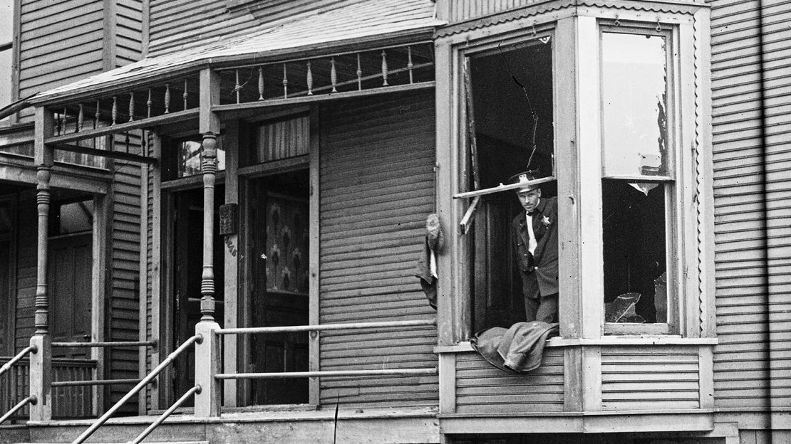 In this 1919 photo provided by the Chicago History Museum, police look through a broken window of a house during the race riots in Chicago. Broken furniture is strewn about the front yard. 