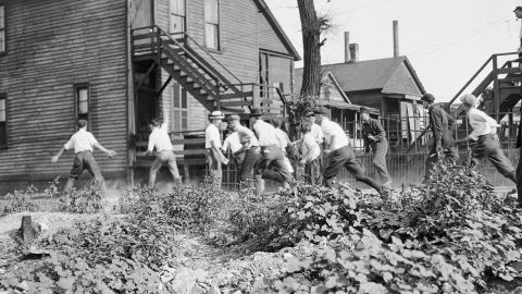 In this 1919 photo provided by the Chicago History Museum, a victim is stoned and bludgeoned under a corner of a house during the race riots in Chicago.
