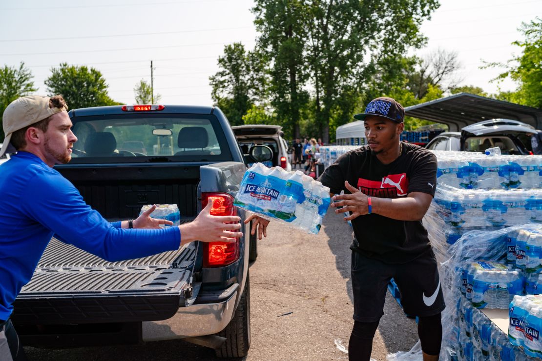 Daevion Marshall, 19, works at Greater Holy Temple Church and delivers cases of water into the cars of residents every week. He throws a case of water to Chris Blanco, a 24-year-old med student volunteer from Indiana University.
