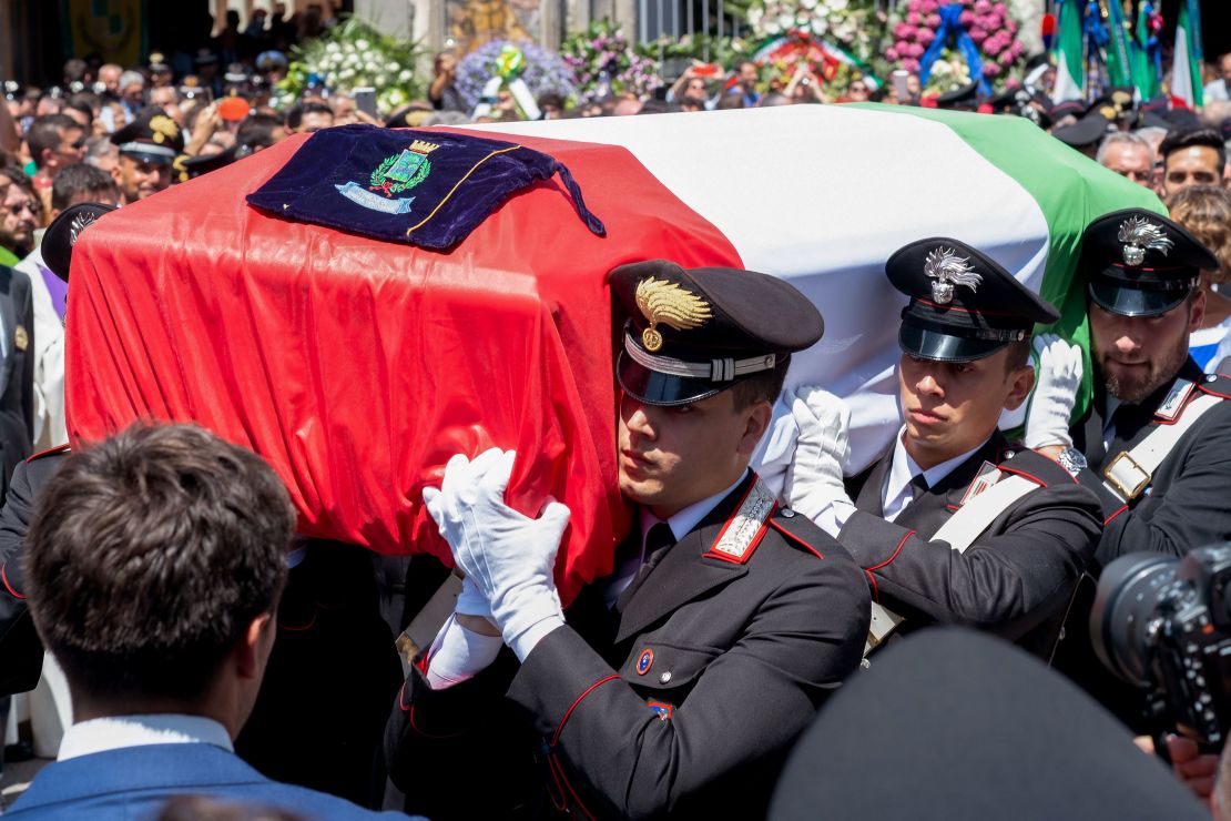 Rega's coffin was draped with the Italian flag. His funeral was attended by hundreds of mourners.