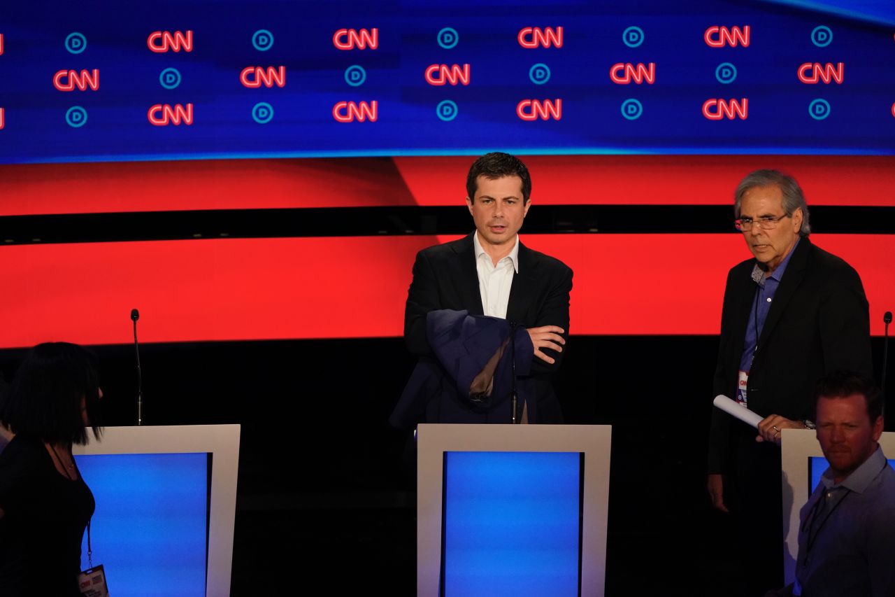 Buttigieg holds a jacket on stage prior to the debate.