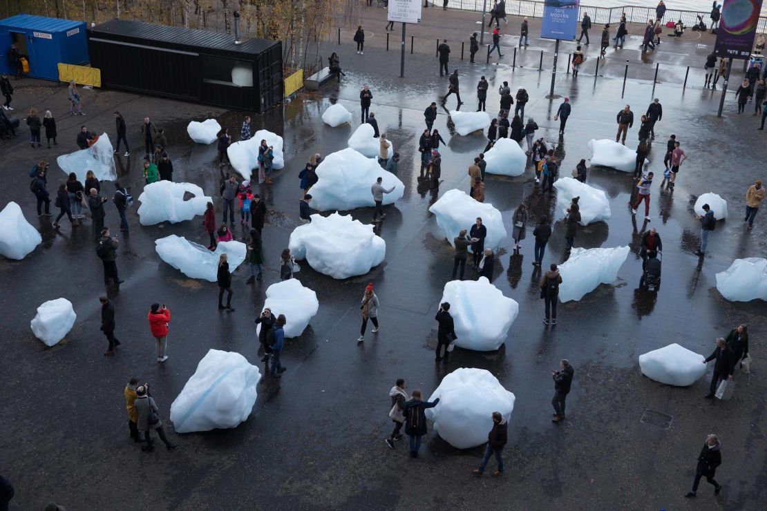 Visitors interact with blocks of melting ice from an exhibit called 'Ice Watch' in central London in December 2018.