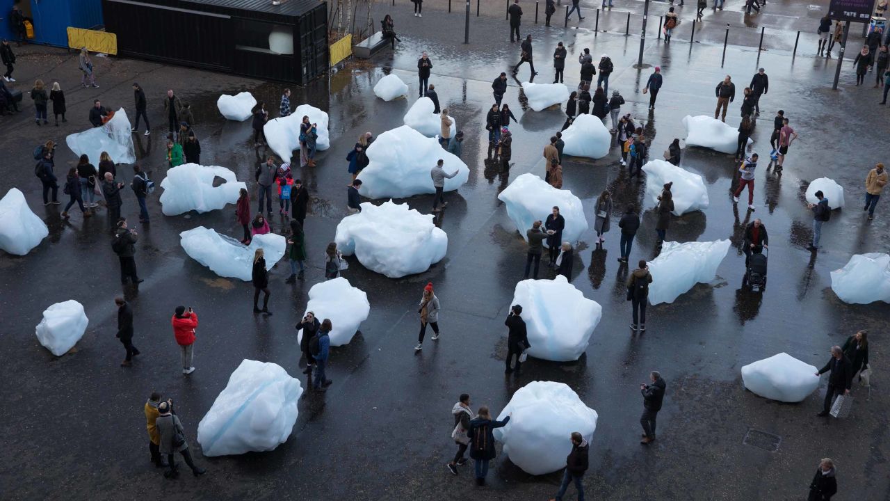 Visitors interact with blocks of melting ice from an exhibit called 'Ice Watch' in central London in December 2018.