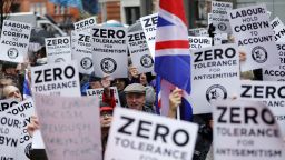 TOPSHOT - People hold up placards and Union flags as they gather for a demonstration organised by the Campaign Against Anti-Semitism outside the head office of the British opposition Labour Party in central London on April 8, 2018. - Labour leader Jeremy Corbyn has been under increasing pressure to address multiple allegations of anti-Semitism within the party, which saw protesters gather outside the party's head office in London after Jewish campaigners demonstrated outside parliament two weeks ago. (Photo by Tolga AKMEN / AFP)        (Photo credit should read TOLGA AKMEN/AFP/Getty Images)