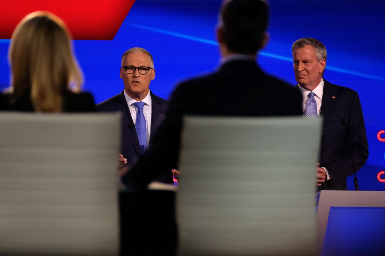Inslee and de Blasio are seen in front of moderators Dana Bash and Jake Tapper.