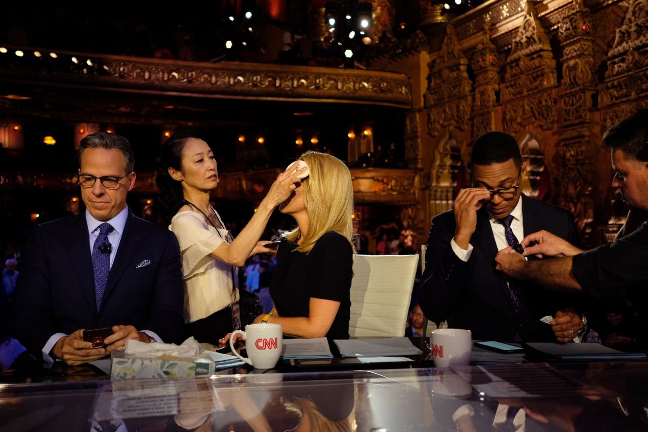 Bash has her makeup retouched during a commercial break Wednesday. Tapper checks his phone while moderator Don Lemon has his microphone adjusted.