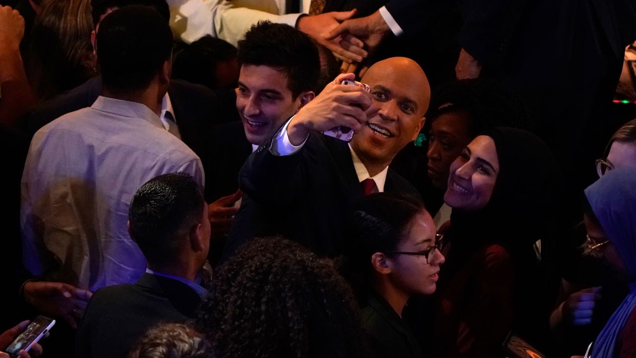 Booker takes a photo while mingling after the debate.