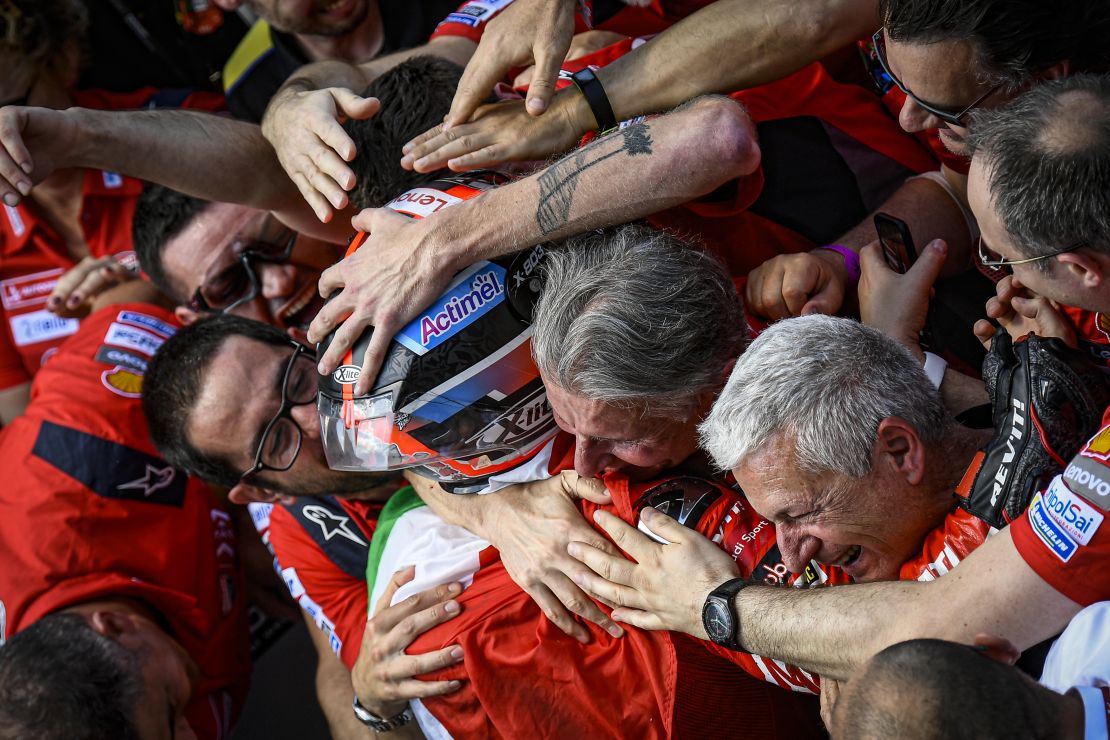 An exhausted, overjoyed Danilo Petrucci is embraced by his Ducati team in Parc Fermé.