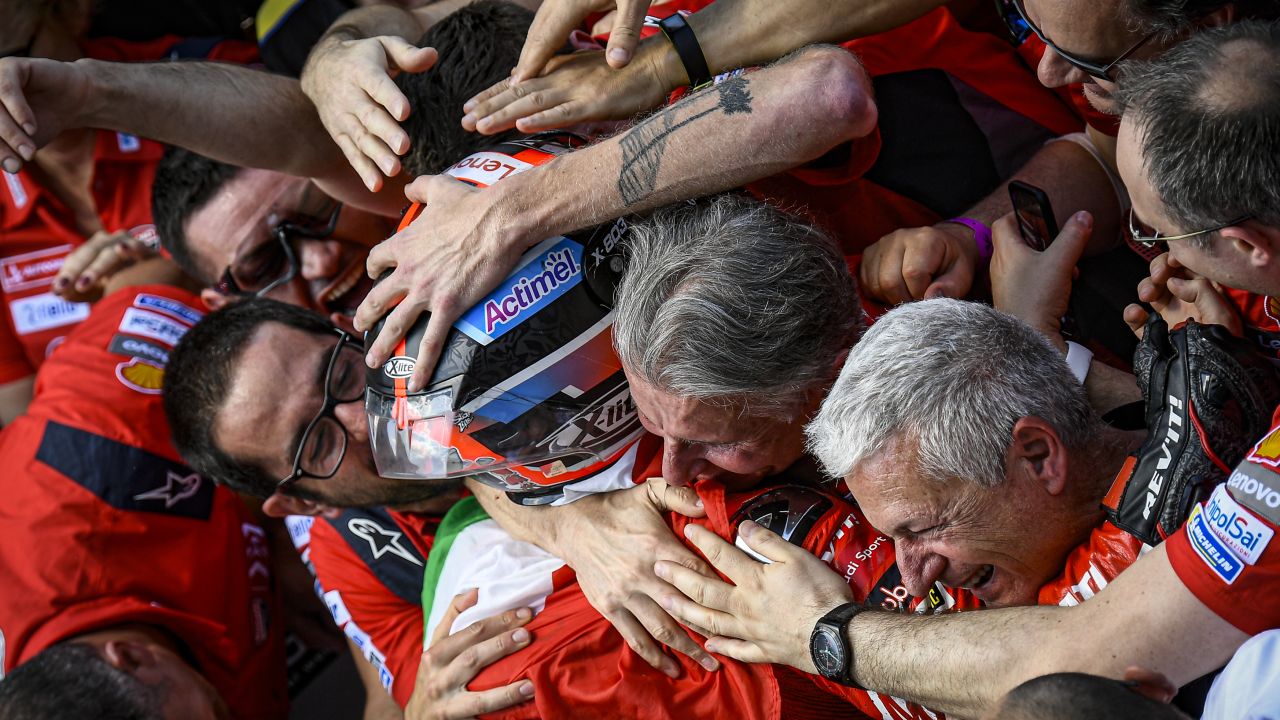 An exhausted, overjoyed Danilo Petrucci is embraced by his Ducati team in Parc Fermé.