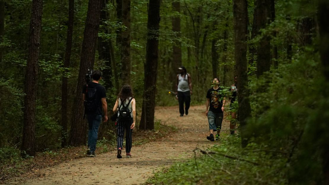 People walk along a smooth, wide trail that leads to the more narrow, rough Doll's Head Trail.