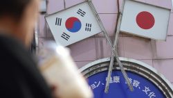 A woman walks past an advertisement featuring Japanese and South Korean flags at a shop in Shin Okubo area in Tokyo Friday, Aug. 2, 2019. Japan has approved the removal of South Korea from a "whitelist" of countries with preferential trade status, escalating tensions between the neighbors. The decision will fuel antagonism between the two neighbors already at a boiling point over the export controls and the issue of compensation for wartime Korean laborers. (AP Photo/Eugene Hoshiko)
