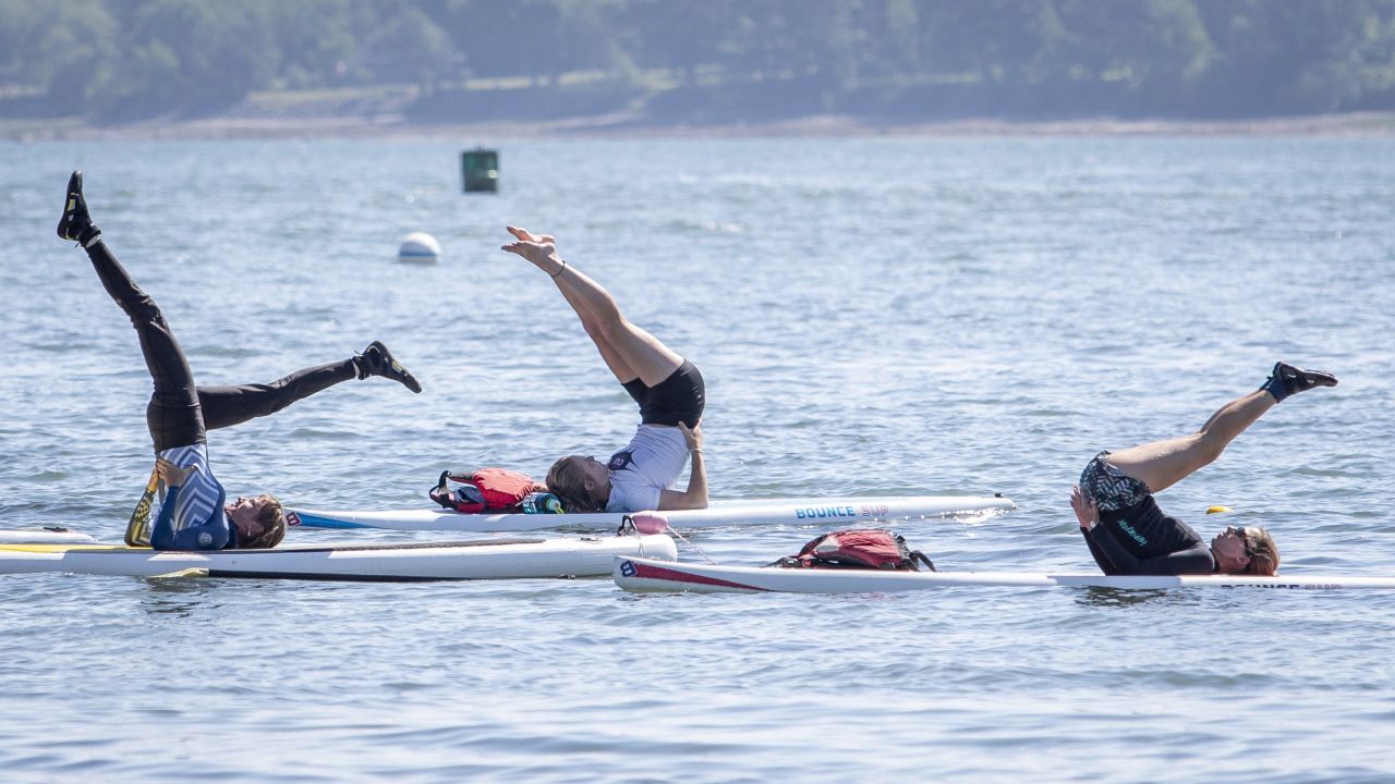 Paddleboard yoga, as seen here in a class in Maine, involves balancing on a paddleboard while doing yoga poses.