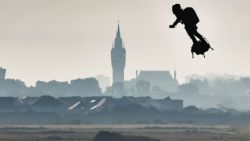 Franky Zapata on his jet-powered "flyboard" flies past the belfry of the city hall of Calais (C) after he took off from Sangatte, northern France, on August 4, 2019, during his attempt to fly across the 35-kilometre (22-mile) Channel crossing in 20 minutes, while keeping an average speed of 140 kilometres an hour (87 mph) at a height of 15-20 metres (50-65 feet) above the sea. - Frenchman who has spent years developing a jet-powered hoverboard will again try to zoom across the English Channel on August 4, after a first attempt last month was cut short when a botched refuelling attempt sent him into the water. (Photo by Denis Charlet / AFP)        (Photo credit should read DENIS CHARLET/AFP/Getty Images)