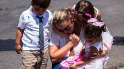Cristina Zapata, 35, second from left, is comforted by her children David Burgos, 4, left, Lucy Burgos, 7, second from right, and Mariana Burgos, 3, right, as they pay their respects to the victims of the El Paso shooting at a memorial in a lot across from the Walmart near Cielo Vista Mall in El Paso, Texas, Sunday, Aug. 4, 2019.