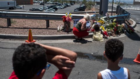 Jessica Windham, 35, top left, and her children Kalani Windham, 2, top right, Andre Newell, 8, bottom left, and Maxwell Windham 5, bottom right, pay their respects to the victims of the shooting at a memorial in a lot across from the Walmart.