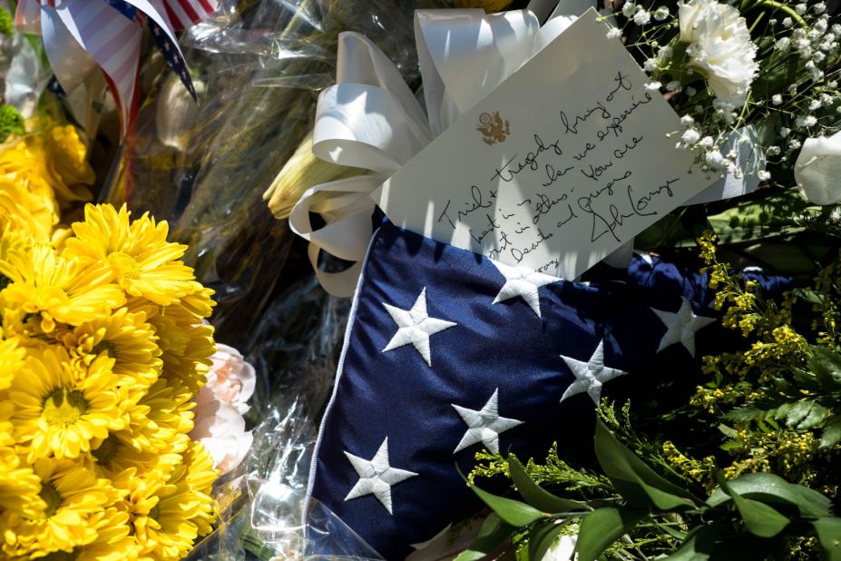 A flag and letter signed by US Sen. John Cornyn is seen on flowers at a makeshift memorial in El Paso.