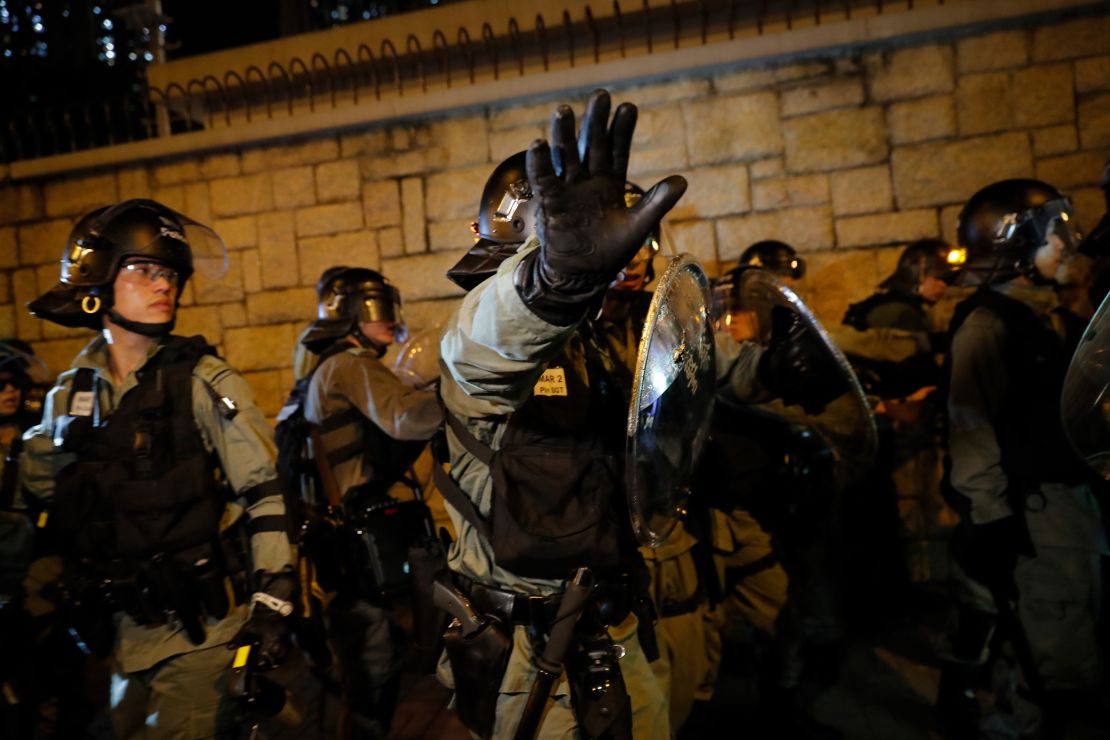 A riot policeman gestures to photographers as they retreat back to Kwun tong police station in Hong Kong, Sunday, August 4, 2019. 