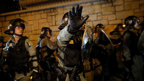 A riot policeman gestures to photographers as they retreat back to Kwun tong police station in Hong Kong, Sunday, August 4, 2019.