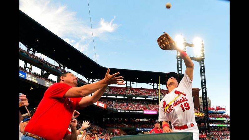 St. Louis Cardinals third baseman Tommy Edman catches a foul ball hit by Chicago Cubs center fielder Ian Happ as a fan reaches for it during the second inning of a game in St. Louis, Missouri, on Wednesday, July 31. 
