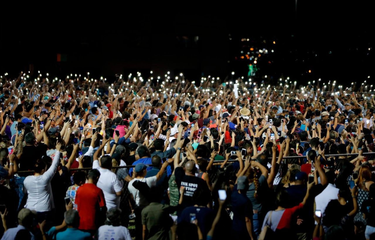 People raise their arms in the air Sunday during a vigil for the El Paso victims.