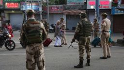 Tourists walk past Indian security forces during curfew like restrictions in Jammu, India, Monday, Aug. 5, 2019. An indefinite security lockdown was in place in the Indian-controlled portion of divided Kashmir on Monday, stranding millions in their homes as authorities also suspended some internet services and deployed thousands of fresh troops around the increasingly tense region. (AP Photo/Channi Anand)